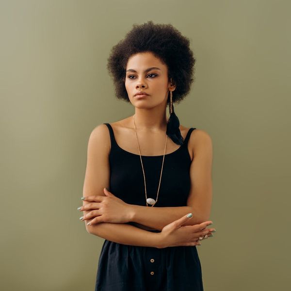 A serene woman meditating with a calm expression against a studio background.